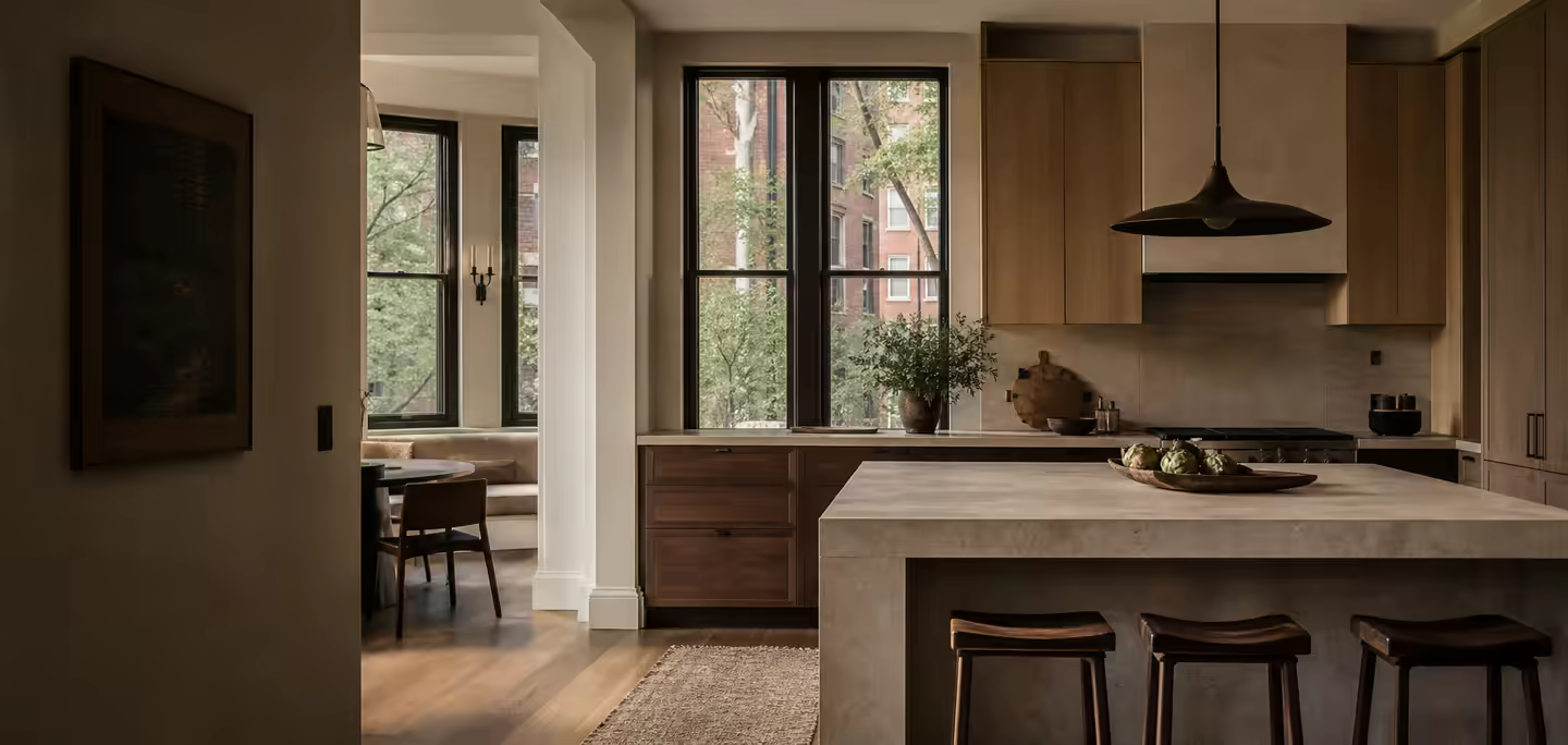 Walnut and limestone kitchen opening toward an urban residential street